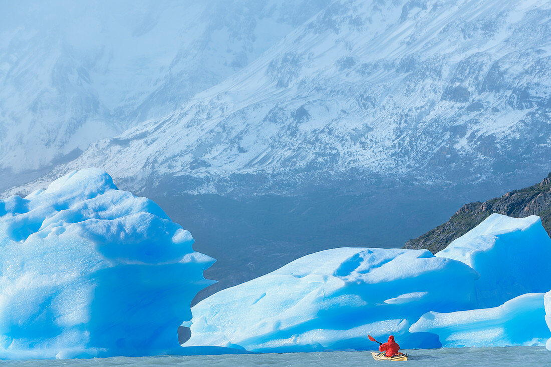 Kajakfahrer paddelt unter Eisbergen, Nationalpark Torres del Paine, Patagonien, Chile, Südamerika