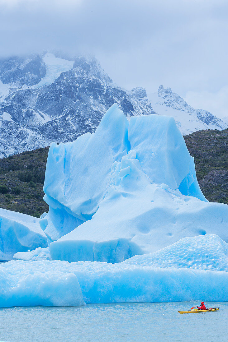 Kajakfahrer paddeln unter Eisbergen, Nationalpark Torres del Paine, Patagonien, Chile, Südamerika