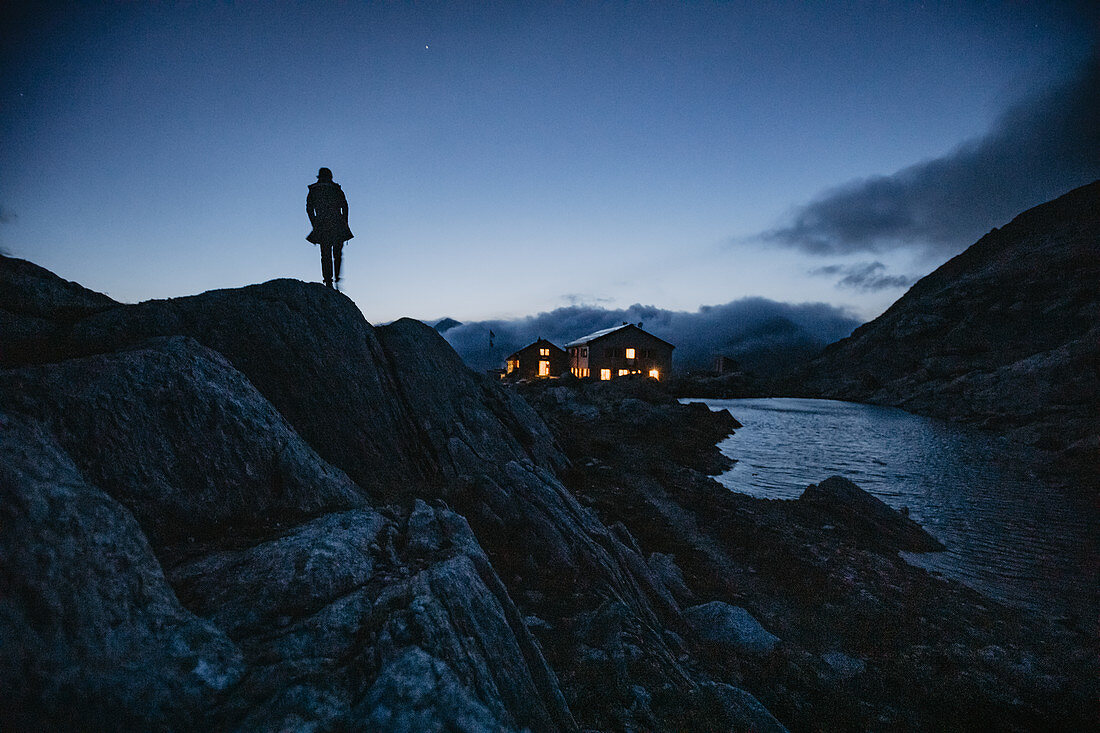 Man stands in front of mountain hut at night in the Swiss mountains, Switzerland, mountain range, mountaineering,