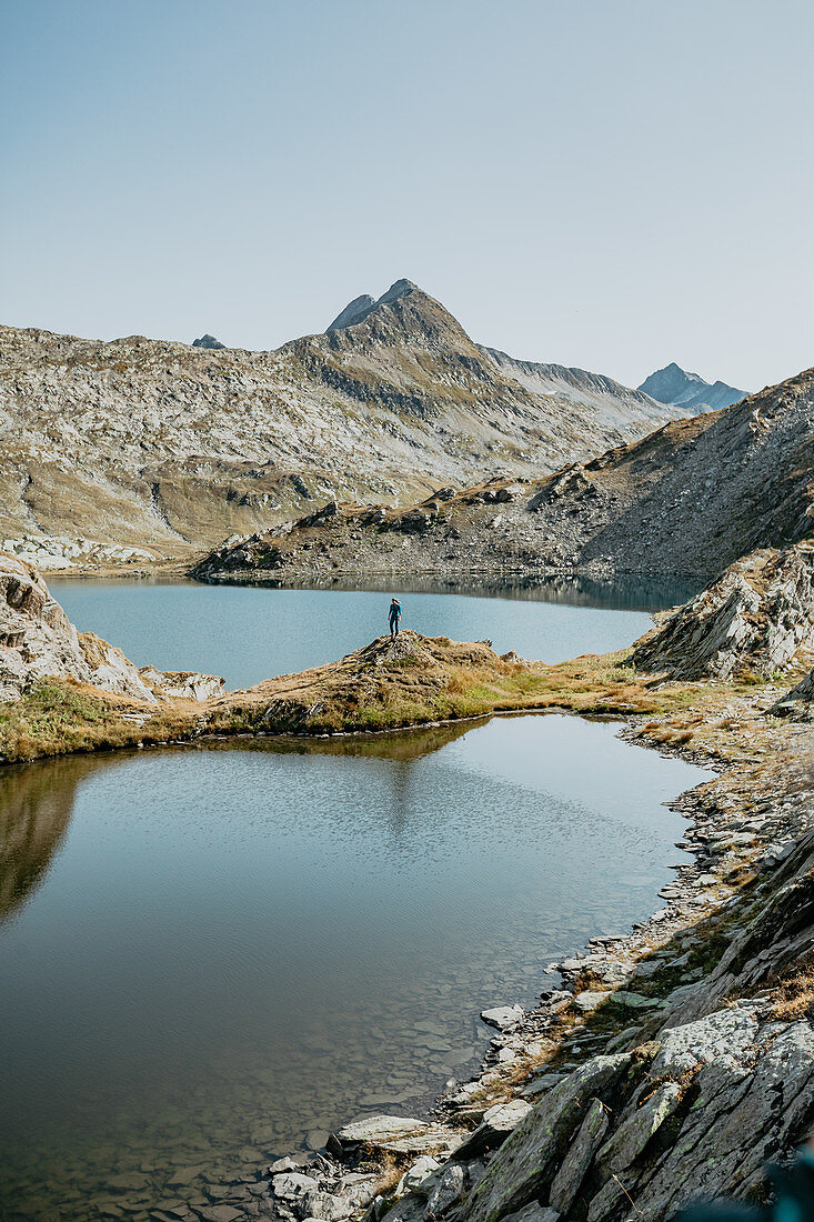 Bergsteigerin steht an einem See mitten im schweizer Bergmassiv, Schweiz