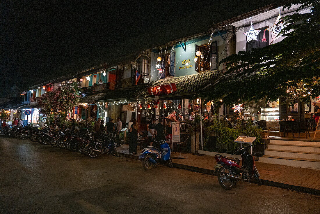 Mopeds stehen vor belebten Restaurant und Bar in der Sisavangvong Road (der Hauptstraße) Gästen im Außenbereich, Luang Prabang, Provinz Luang Prabang, Laos, Asien