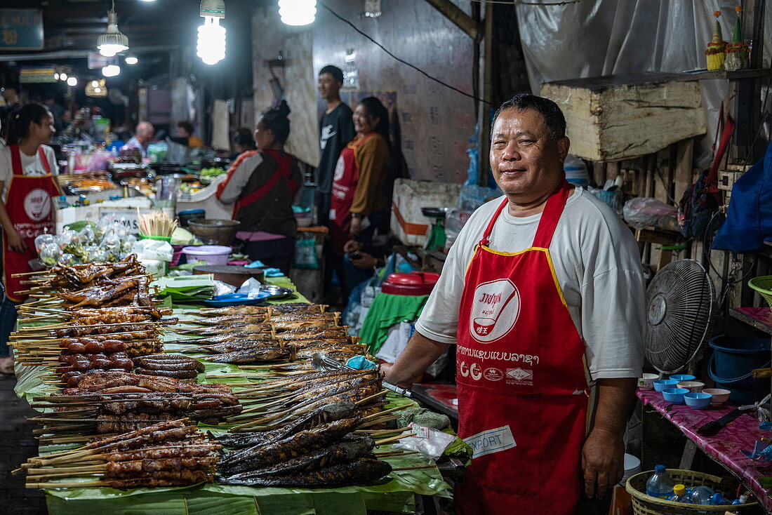 Mann verkauft perfekt gegrillte Fischspieße auf dem Nachtmarkt, Luang Prabang, Provinz Luang Prabang, Laos, Asien