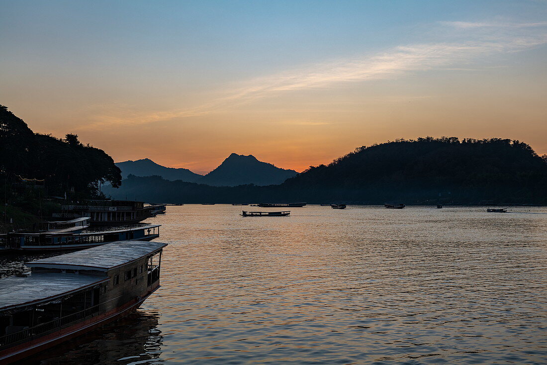 Tourist excursion boats lie on the banks of the Mekong River at sunset, Luang Prabang, Luang Prabang Province, Laos, Asia