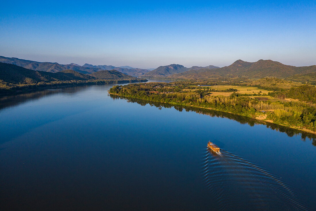 Luftaufnahme von Flusskreuzfahrtschiff Mekong Sun auf Fluss Mekong mit Bergen dahinter, Bezirk Chomphet, Provinz Luang Prabang, Laos, Asien