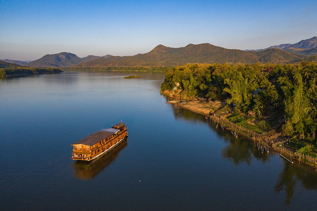 Luftaufnahme von Flusskreuzfahrtschiff Mekong Sun  auf Fluss Mekong mit Bergen dahinter, Bezirk Chomphet, Provinz Luang Prabang, Laos, Asien