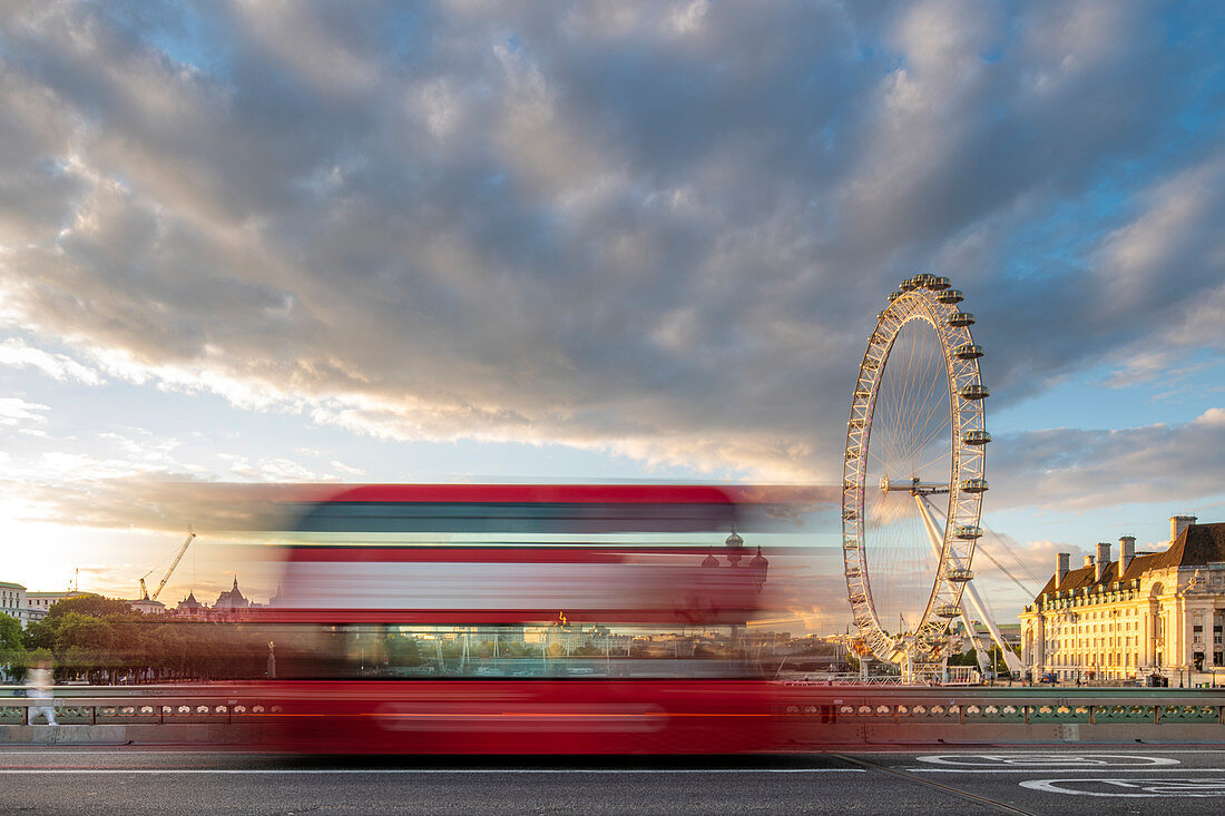 Ein roter Londoner Bus fährt verschwommen über die Westminster Bridge mit dem London Eye und der Southbank in der Ferne, London, England, Großbritannien, Europa