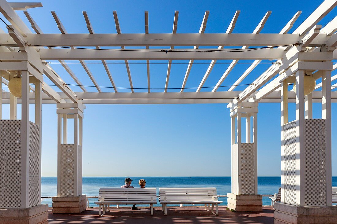 Frankreich, Alpes Maritimes, Nizza, Promenade des Anglais, Paar sitzt auf einer Bank gegenüber der Baie des Anges