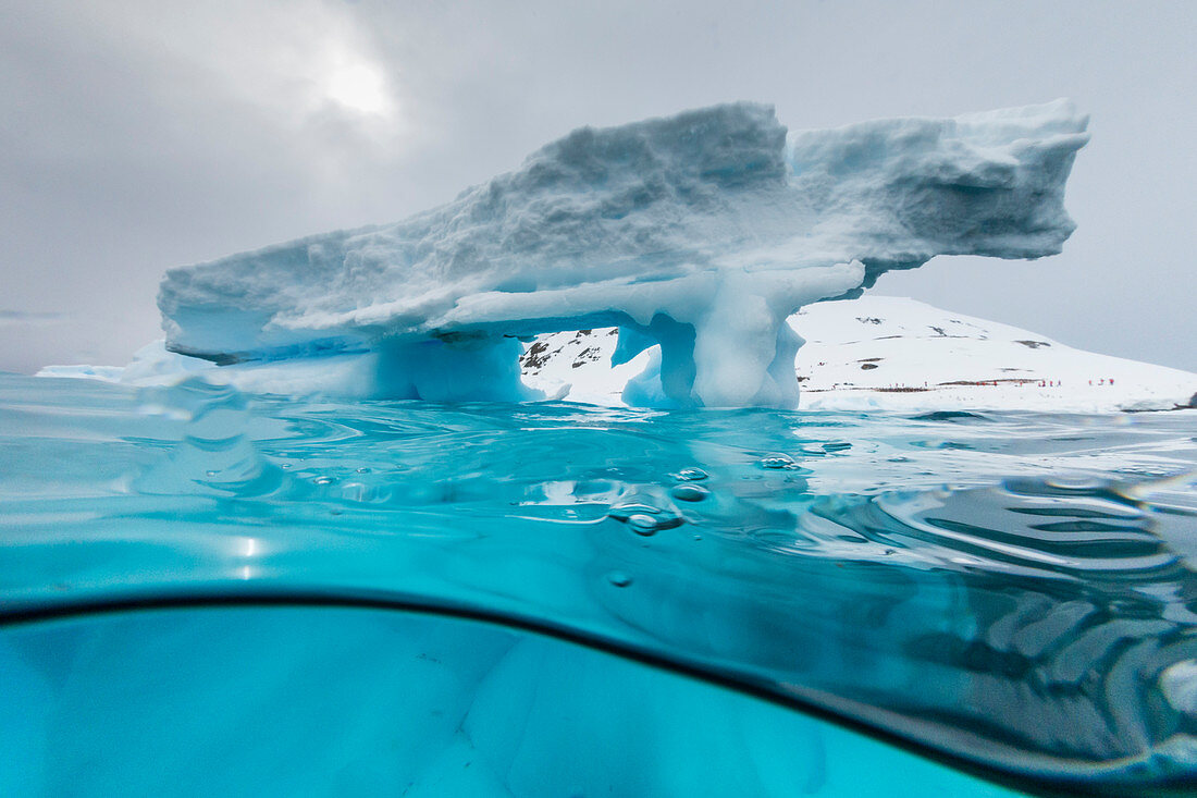 Ober- und Unteransicht eines Bogens, der in einem Eisberg auf Cuverville Island, Ererra-Kanal, Antarktis, Polarregionen gebildet wurde