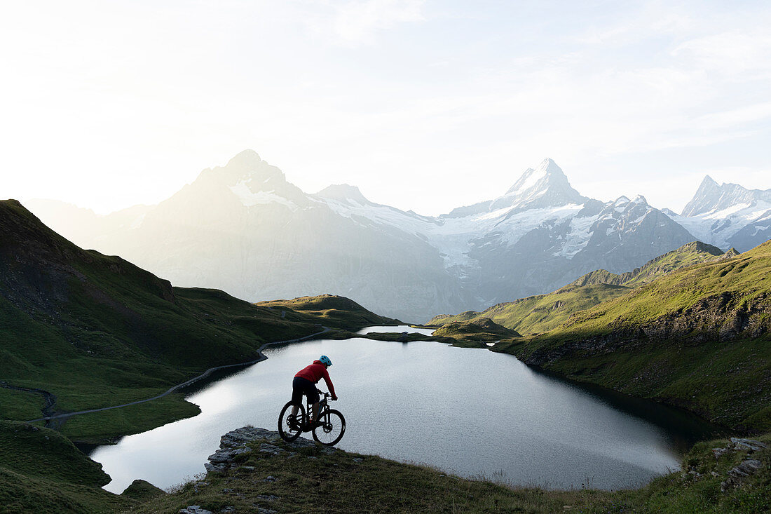 Mountainbiker, der bergab am Bachalpsee im Morgengrauen, Grindelwald, Berner Oberland, Kanton Bern, Schweiz, Europa reitet