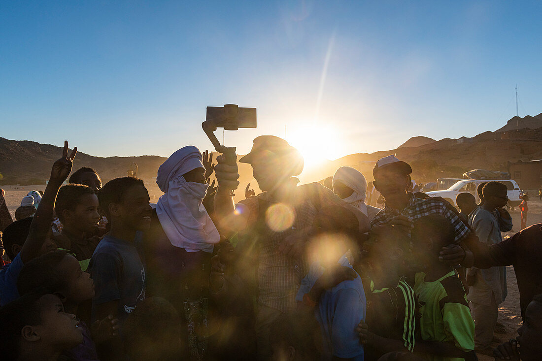 Hintergrundbeleuchtung einer Menge von Kindern und Tuareg-Männern, Oase von Timia, Luftberge, Niger, Afrika