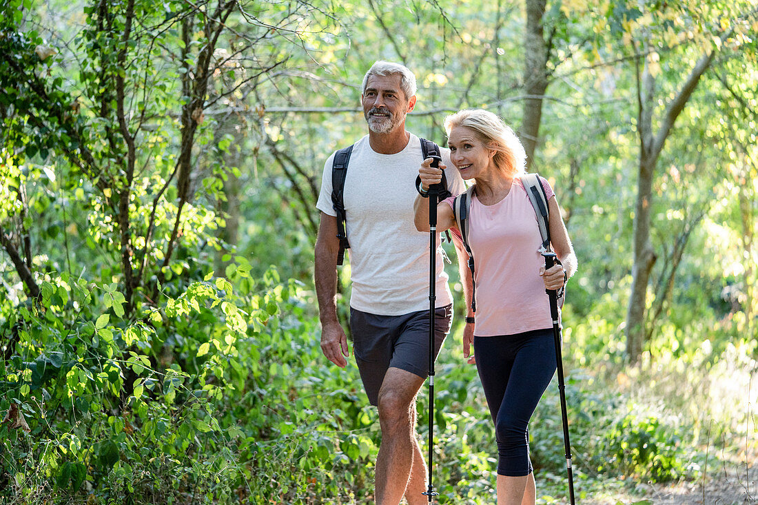 Smiling mature woman showing direction to her husband while hiking in forest