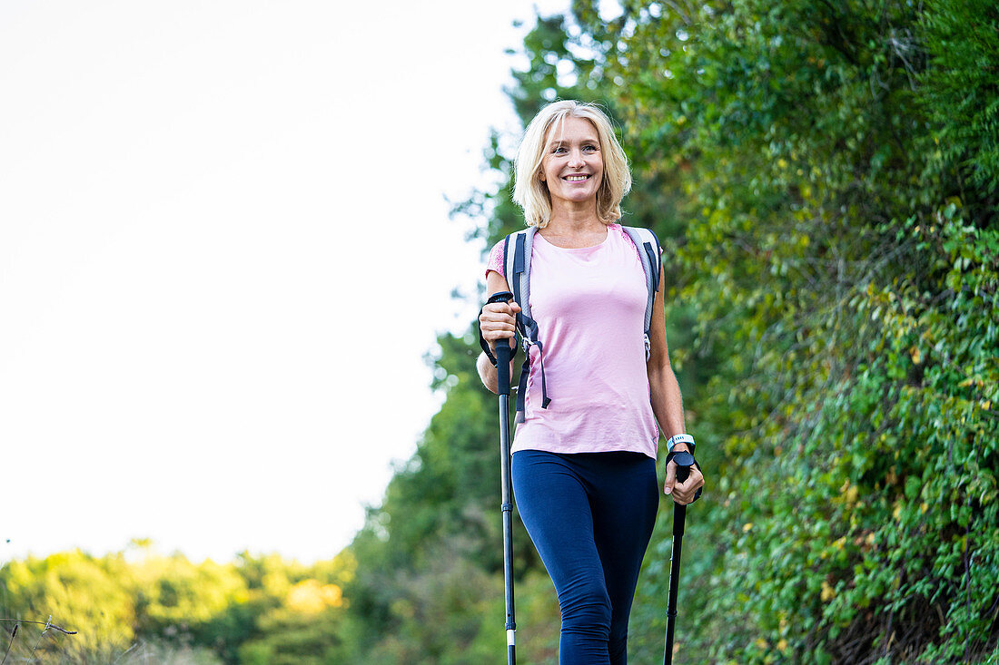 Low angle view of smiling mature woman hiking in forest