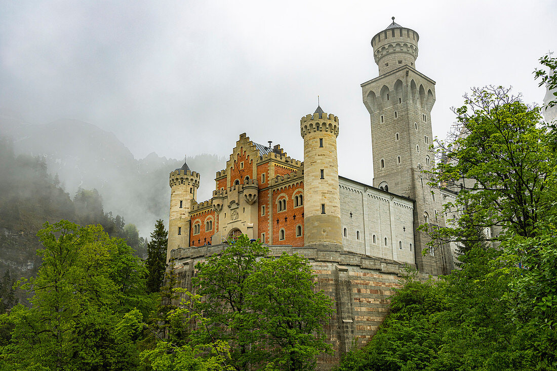 Blick auf Schloss Neuschwanstein mit Wolken und grünen Wäldern, Schwangau, Oberbayern, Deutschland
