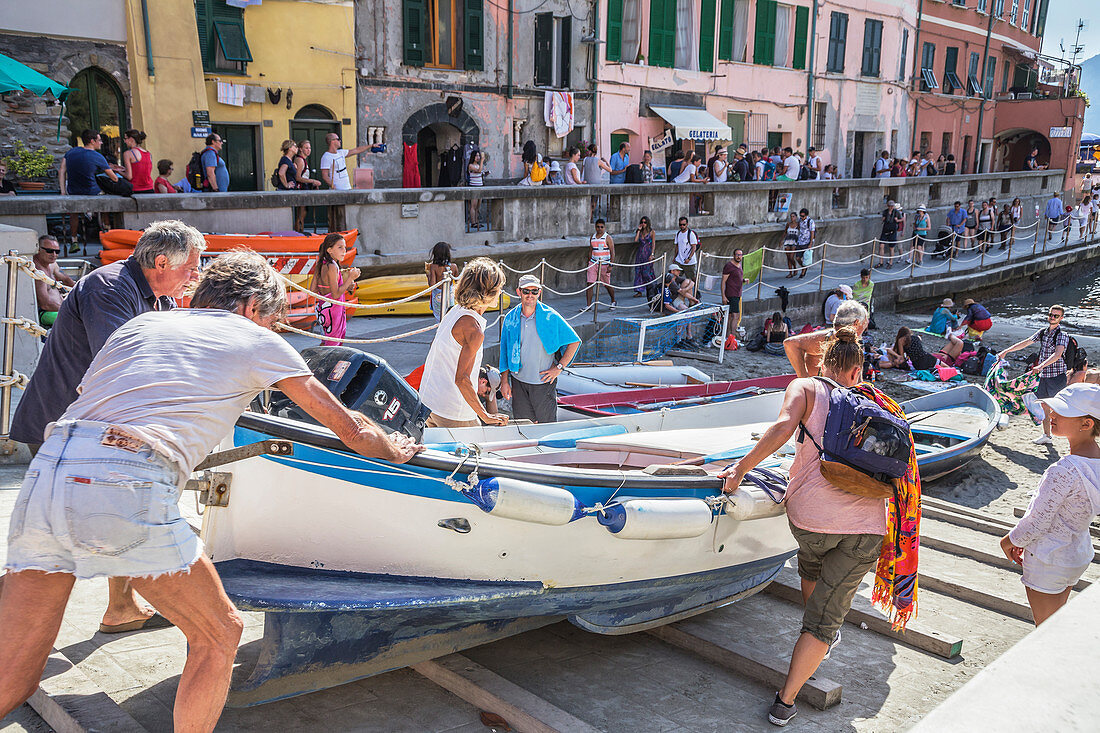 People pushing fishing boat into the sea, Vernazza, Cinque Terre, Liguria, Italy, Europe