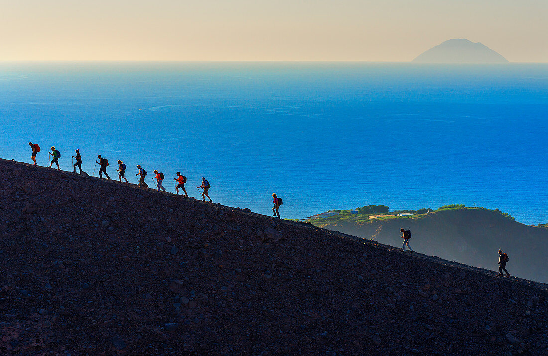 Hikers walking around Gran Crater rim, Vulcano Island, Aeolian Islands, Sicily, Italy