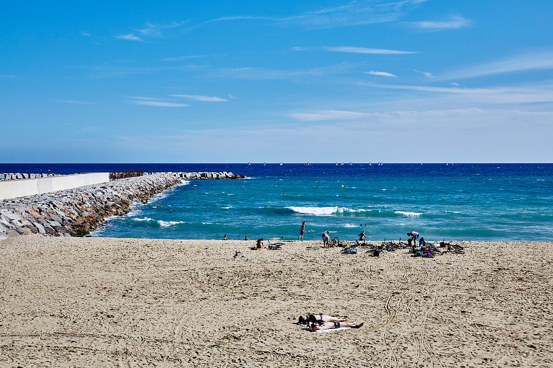 A wide view of the breakwater and people on the beach at Barceloneta, Barcelona, Catalonia Spain