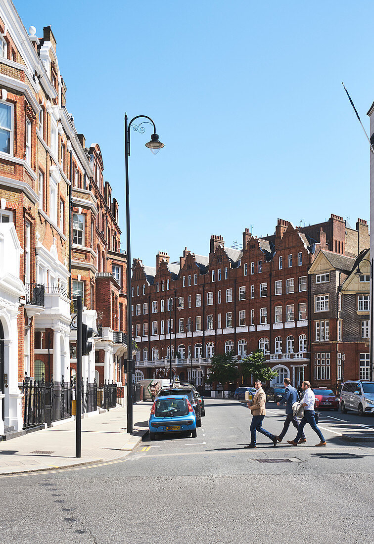 Männer überqueren eine Straße in Kensington an einem sonnigen Tag, London UK