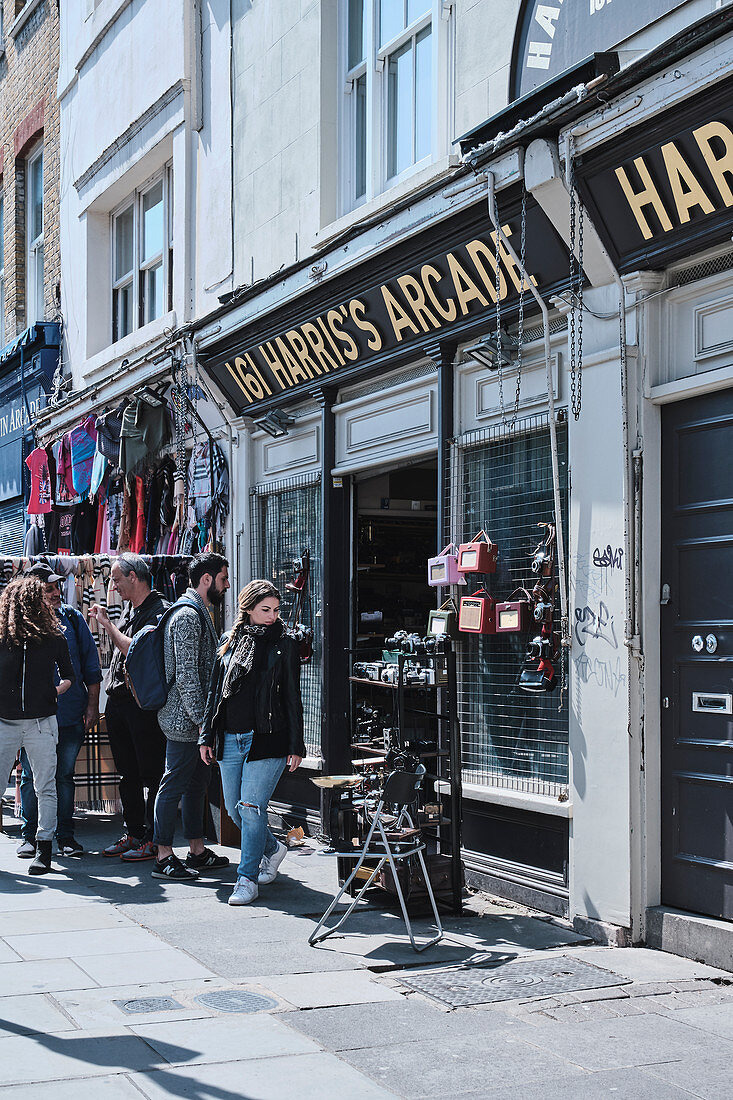 Streetscape of a camera shop and people on Portobello Road, Notting Hill, London UK