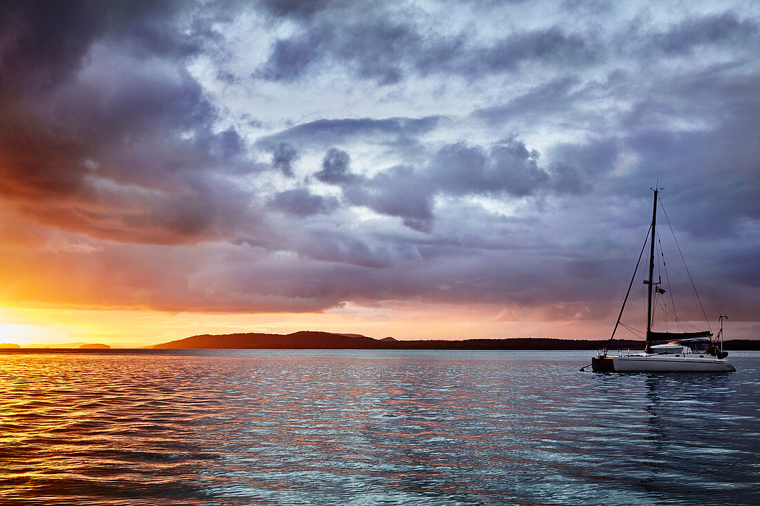 Sonnenuntergang in Nelson Bay, New South Wales, Australien während ein Sturm über die auf dem Wasser vertäuten Boote hinwegzieht