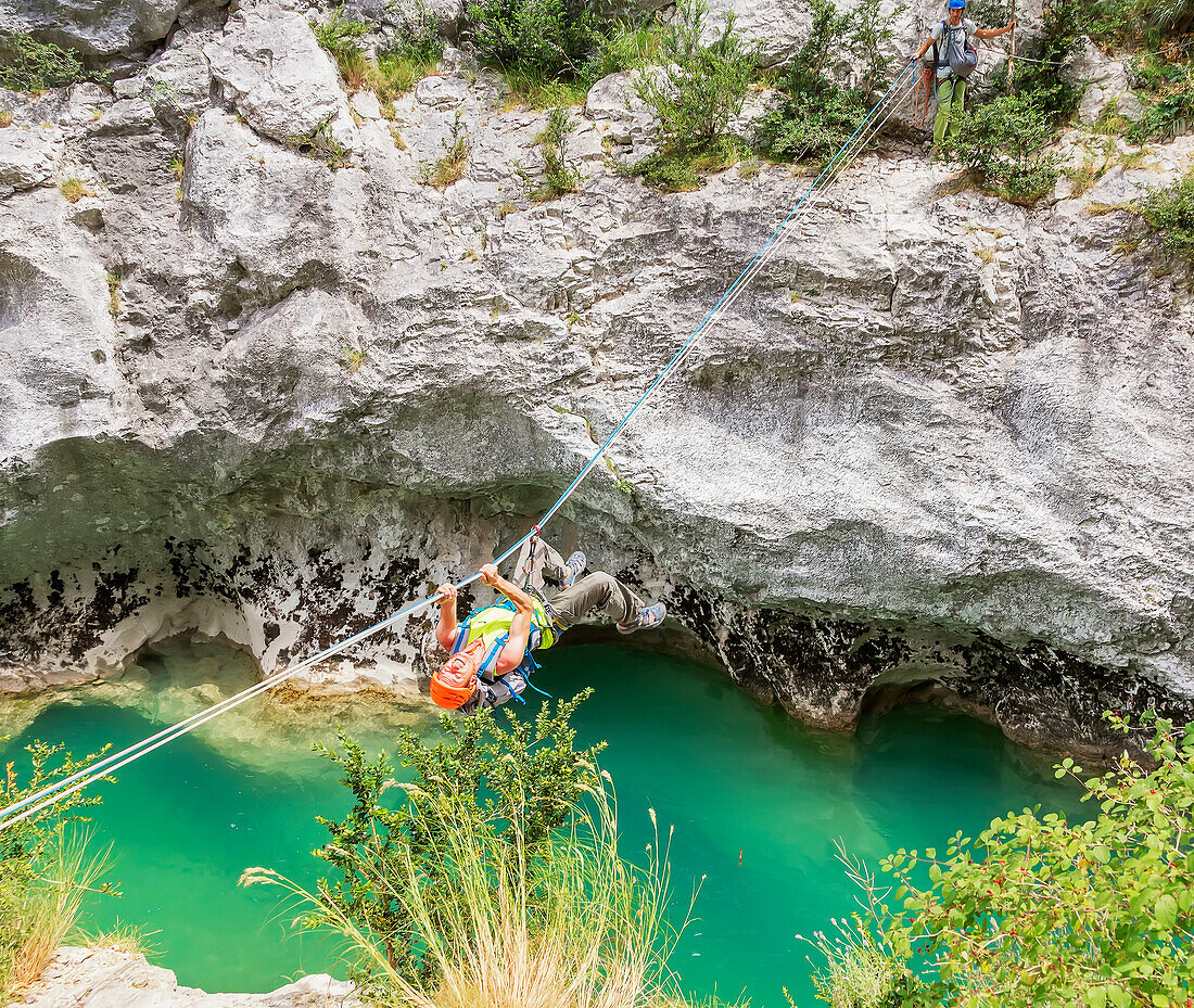 Mann überquert den Fluss Verdon an einem Seil, Gorges du Verdon, Alpes-de-Haute-Provence, Provence, Frankreich