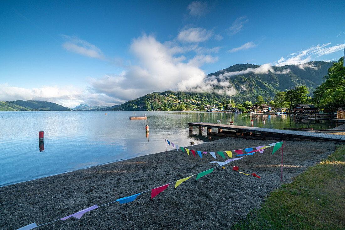 View over Lake Millstatt from the beach on the east bank of the alpine mountain and cultural landscape, Döbriach, Carinthia; Austria, Europe.