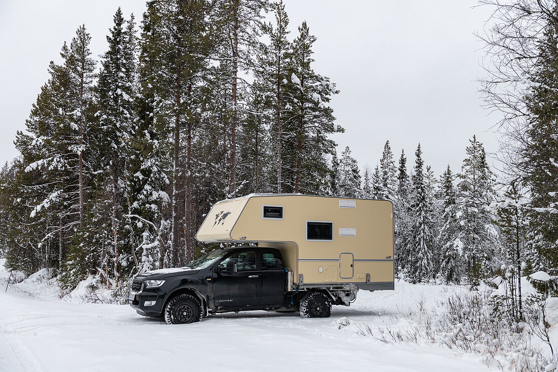 Van on snowy road in the forest in winter, near Arvidsjaur, Lapland, Sweden