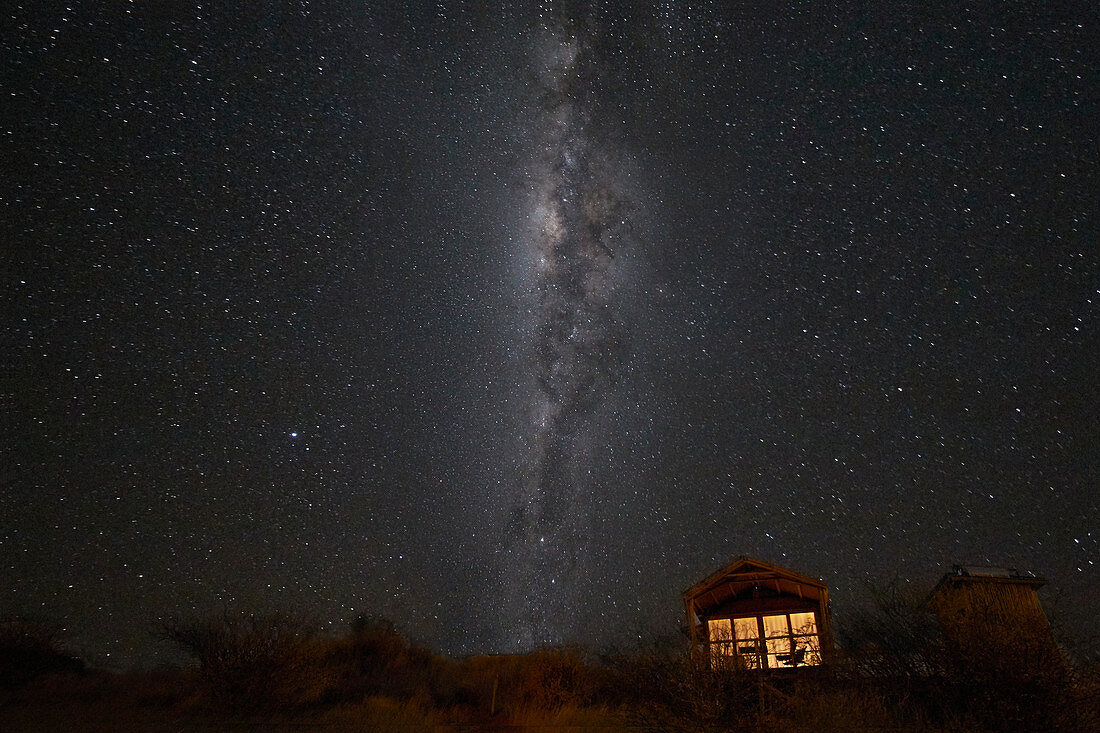 Milchstraße der Südhalbkugel und eine kleine beleuchtete Hütte, Namibia, Afrika