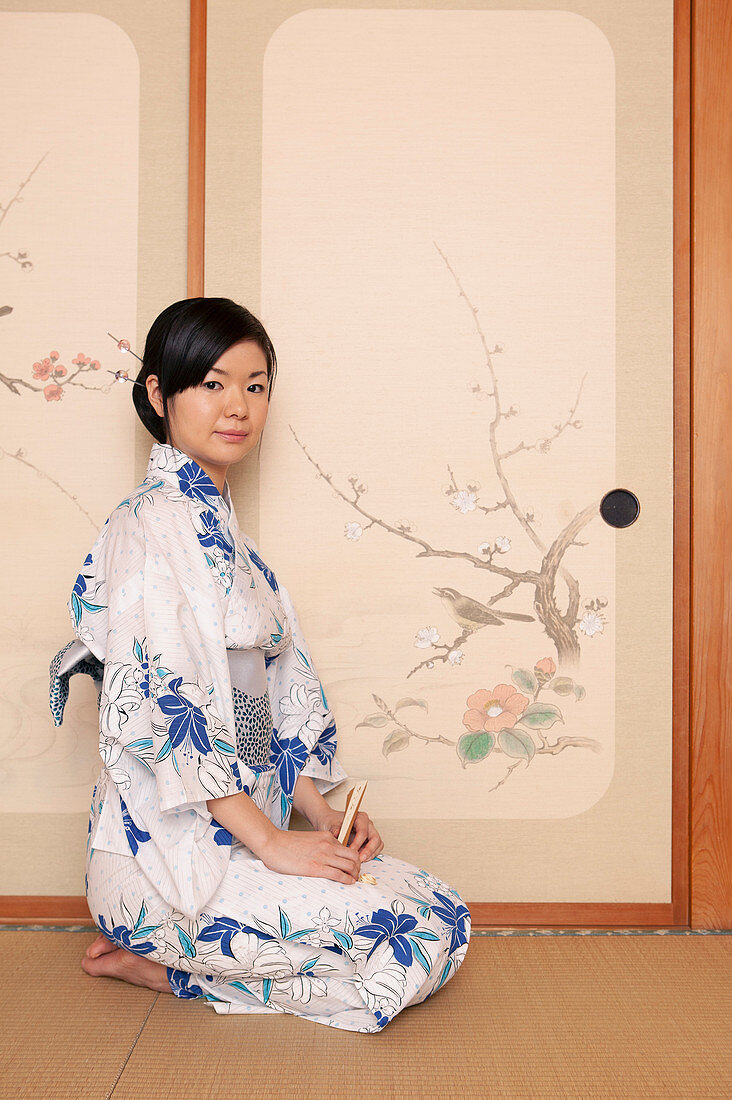 Schöne junge Japanerin im Kimono an der bemalten Tür