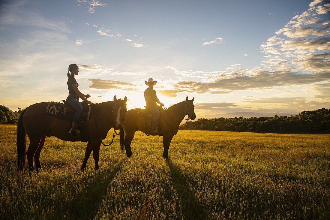USA, Utah, Salem, Vater und Tochter (14-15 Jahre) Reitpferde bei Sonnenuntergang