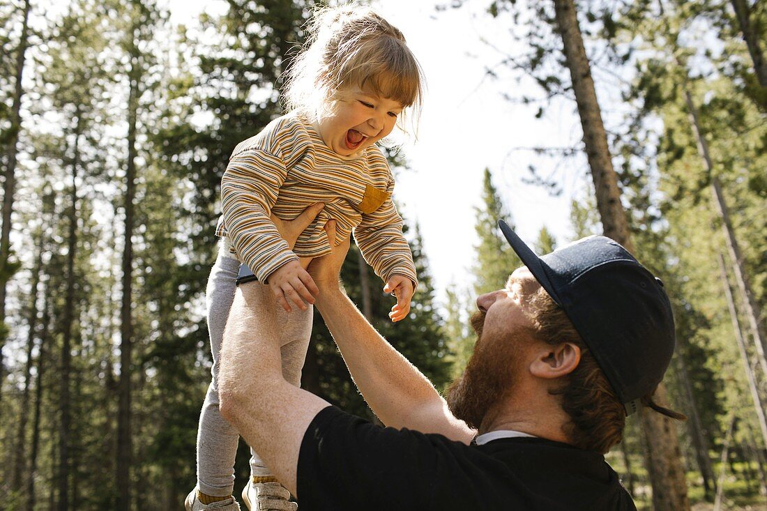 Vater hält lächelnde Tochter (2-3 Jahre) im Wald, Wasatch-Cache National Forest