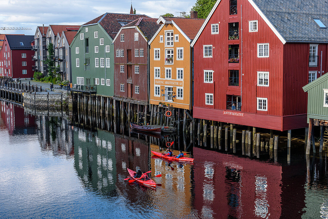 Kayakers in front of old warehouses along the Nidelva ,, Trondheim, Norway