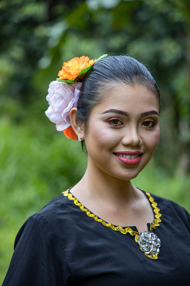 Portrait of a cheerful young woman in traditional costume in the Sarawak Cultural Village, near Kuching, Sarawak, Borneo, Malaysia, Asia