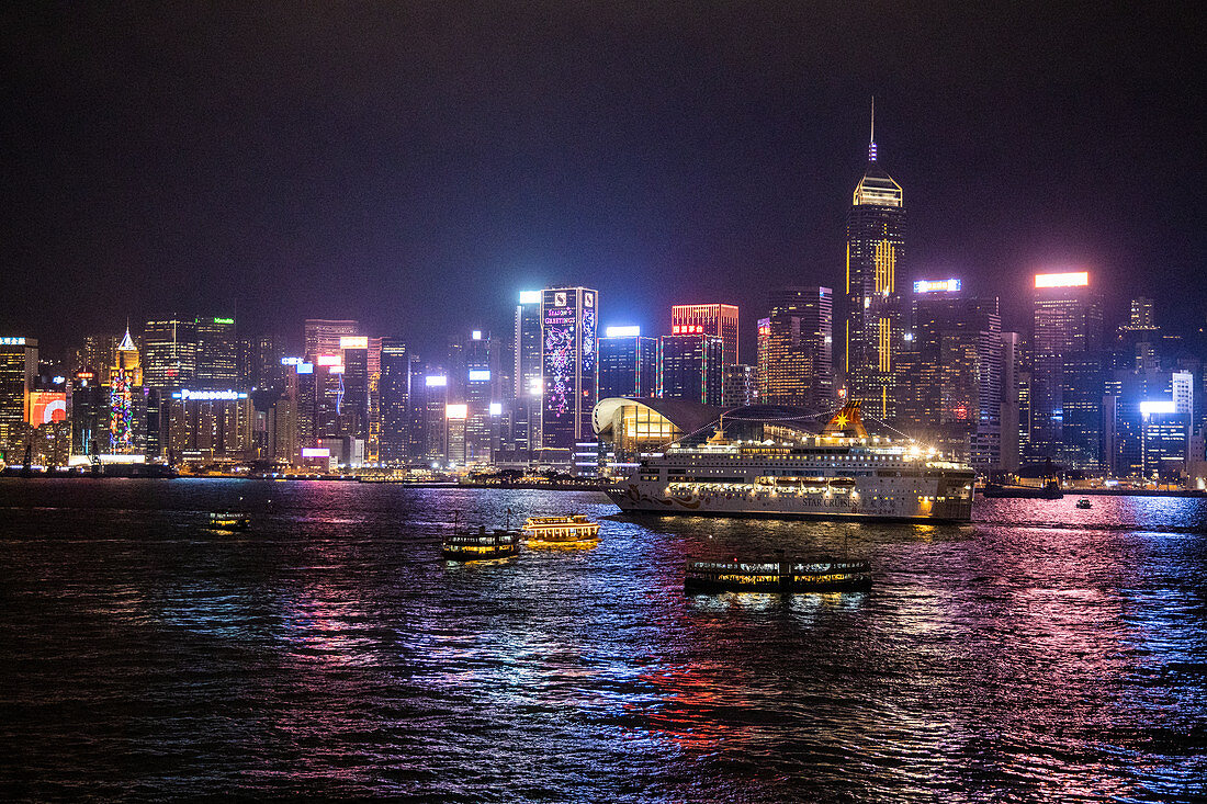 Cruise ship Pisces in Victoria Harbor with city skyline at night, Hong Kong, Hong Kong, China, Asia