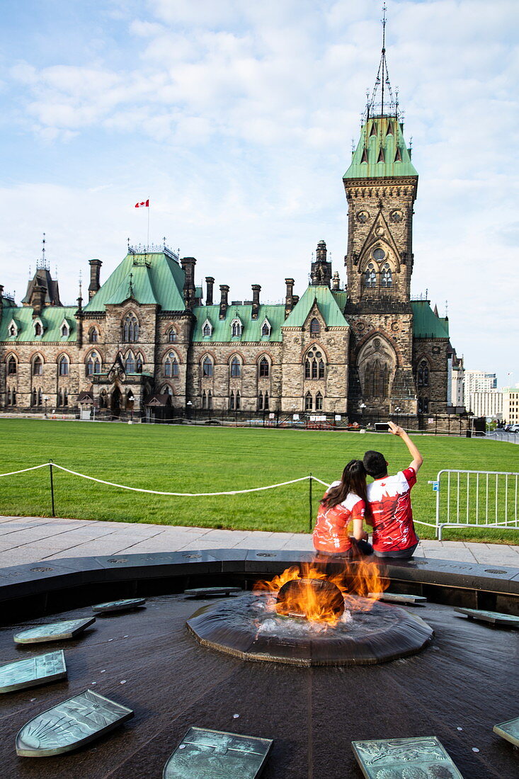 Tourists take selfie photo by the Eternal Flame in front of the Parliament Building, Ottawa, Ontario, Canada, North America