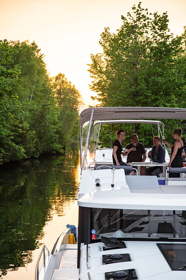 Menschen genießen Wein an Bord von einem Le Boat Horizon Hausboot, das bei Sonnenuntergang an den Schleusen Beveridge Locks entlang vom Fluss Tay River angedockt ist, nahe Lower Rideau Lake, Ontario, Kanada, Nordamerika