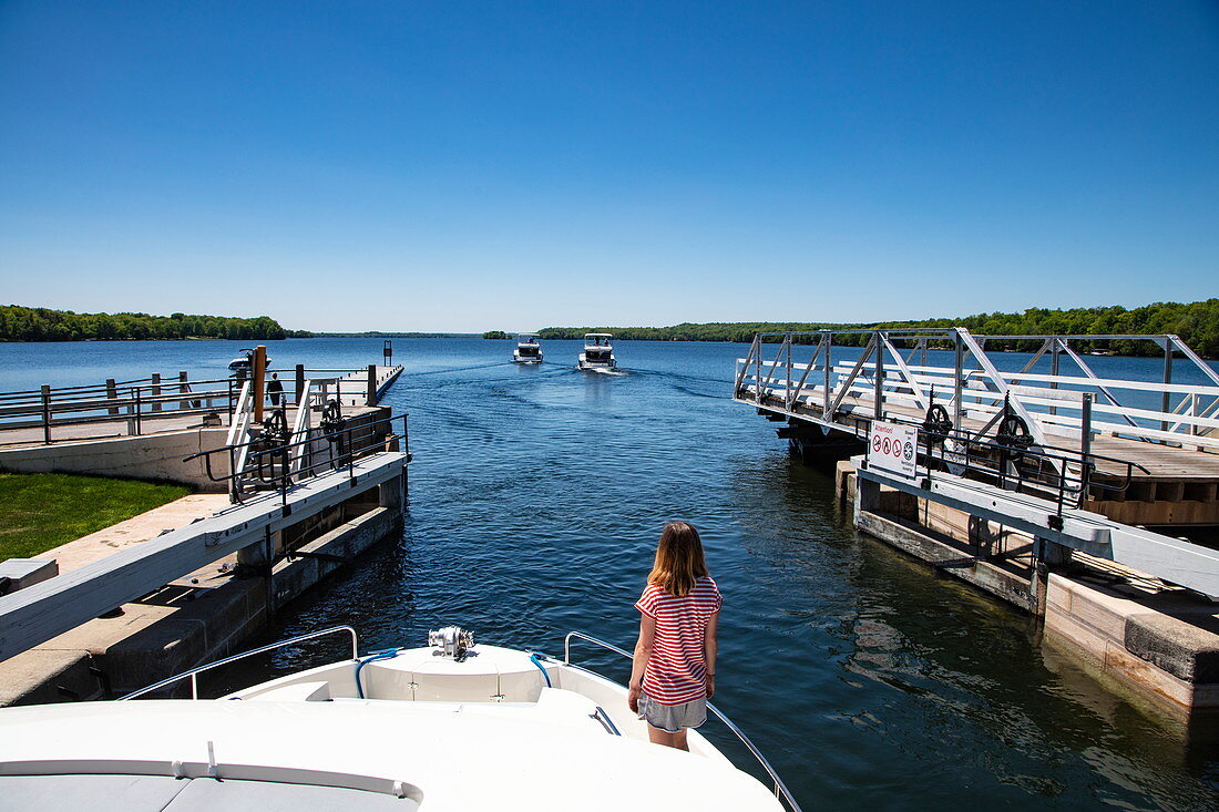 Young woman on the bow of a Le Boat Horizon houseboat in the lock at the Narrows Lockstation, Big Rideau Lake, Ontario, Canada, North America