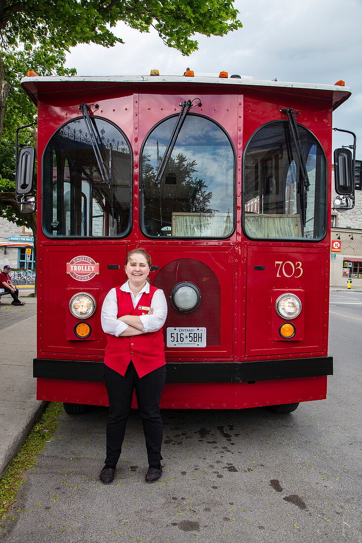 Woman driver stands in front of red tourist bus, Kingston, Ontario, Canada, North America