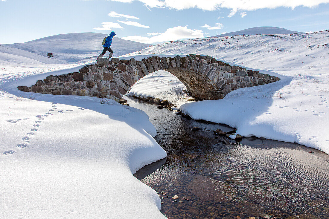 Wanderer auf Steinbrücke, Old Miltary Road im Schnee, Corgarff, Lecht Road, Cairngorms, Highlands, Aberdeenshire, Schottland, UK