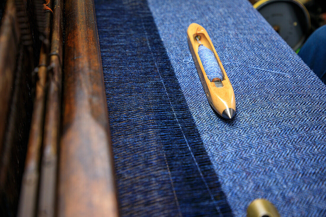 Weaver's shuttle lies on tweed fabric, Isle of Harris, Outer Hebrides, Scotland UK