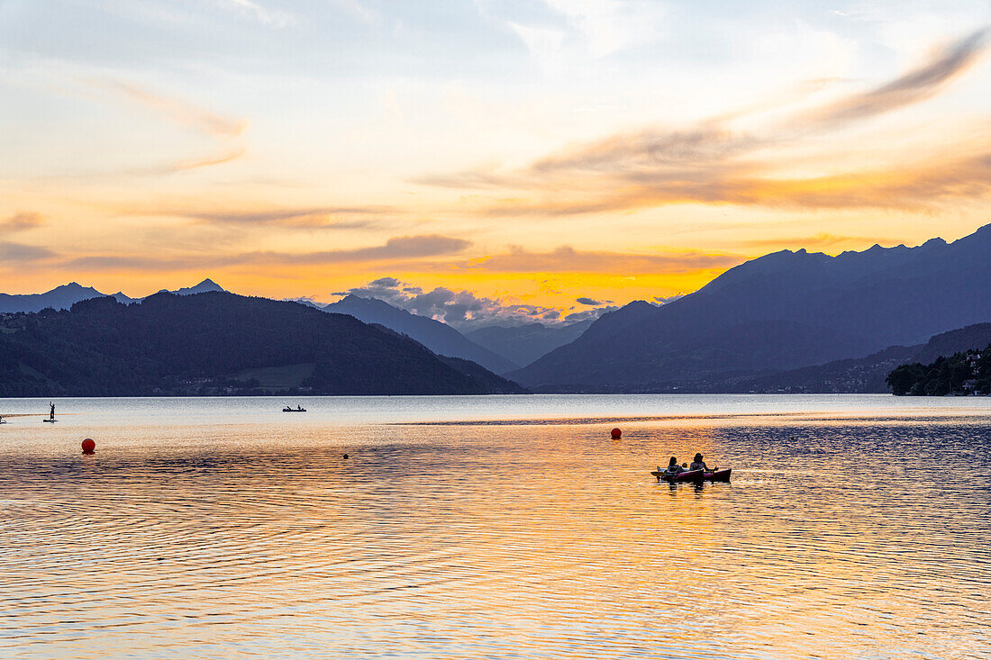 Sunset over Lake Millstatt. Bathing fun on the beach. In the background you can see the alpine mountain landscape, Carinthia; Austria, Europe