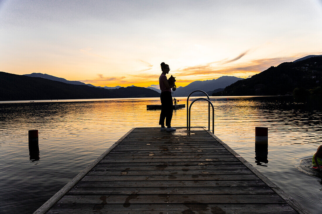 Sunset over Lake Millstatt. Bathing fun on the beach. In the background you can see the alpine mountain landscape, Carinthia; Austria, Europe