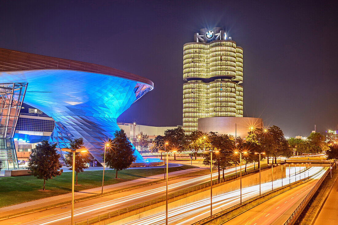 Blue illuminated BMW Welt building with BMW four-cylinder and BMW Museum in the background and Georg-Brauchle-Ring in the foreground, Munich, Upper Bavaria, Bavaria, Germany