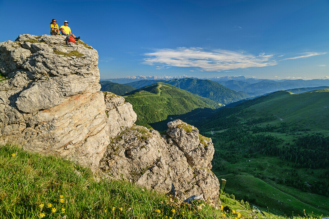 Man and woman while hiking sit on Felskanzel, Predigerstuhl, Nockberge, Nockberge-Trail, UNESCO Biosphere Park Nockberge, Gurktal Alps, Carinthia, Austria