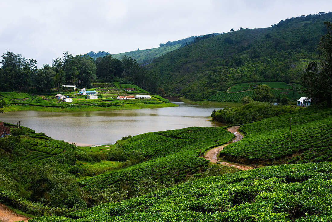 Dorf am Ufer des Manalar-Flusses, umgeben von Teeplantagen in Megamalai, Tamil Nadu, Indien