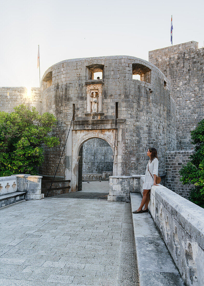 Frau genießt den Sonnenaufang am Pile Tor der Altstadt von Dubrovnik, Dalmatien, Kroatien.