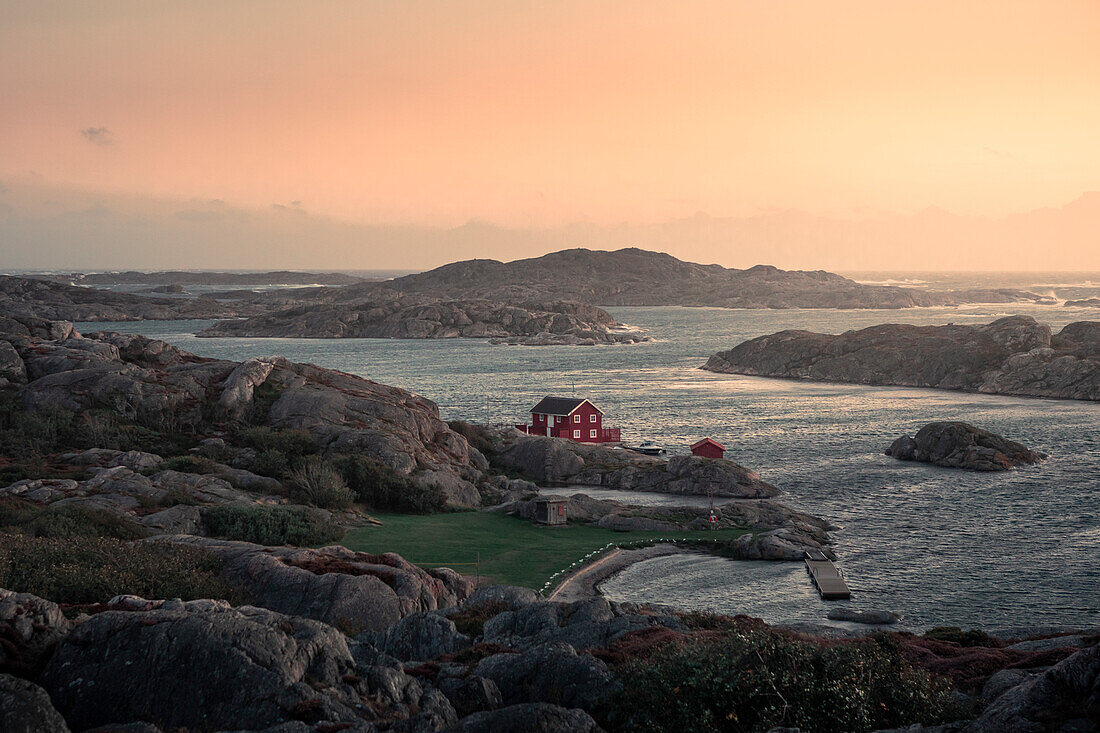Rote Hütte an der Küste bei Skärhamn auf der Schäreninsel Tjörn an der Westküste von Schweden im Sonnenuntergang\n