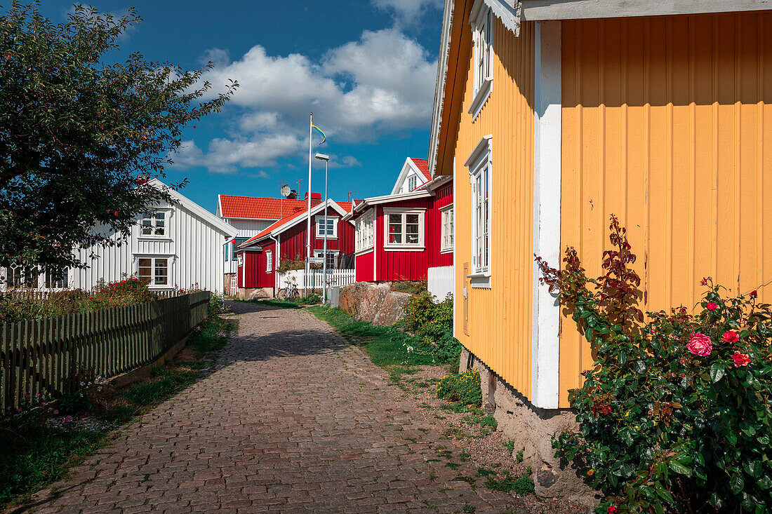 Gasse mit bunten Häusern im Dorf Mollösund auf der Schäreninsel Orust an der Westküste von Schweden, Sonne am Tag mit blauem Himmel\n