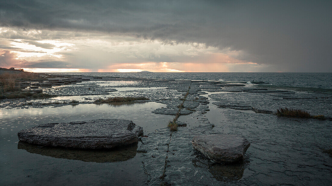 Felsküste im Westen der Insel Öland in Schweden bei Regen im Sonnenuntergang 