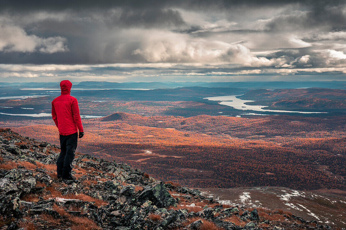 Wanderer blickt über Landschaft mit Seen im Pieljekaise Nationalpark im Herbst in Lappland in Schweden\n
