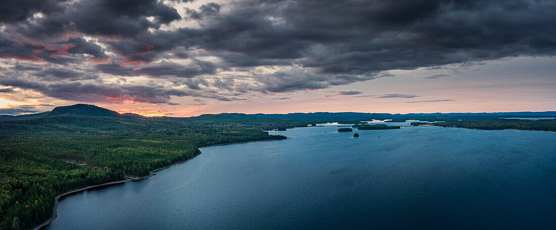 Wald und Seeufer am Siljansee von oben im Sonnenuntergang mit Wolken in Dalarna, Schweden\n